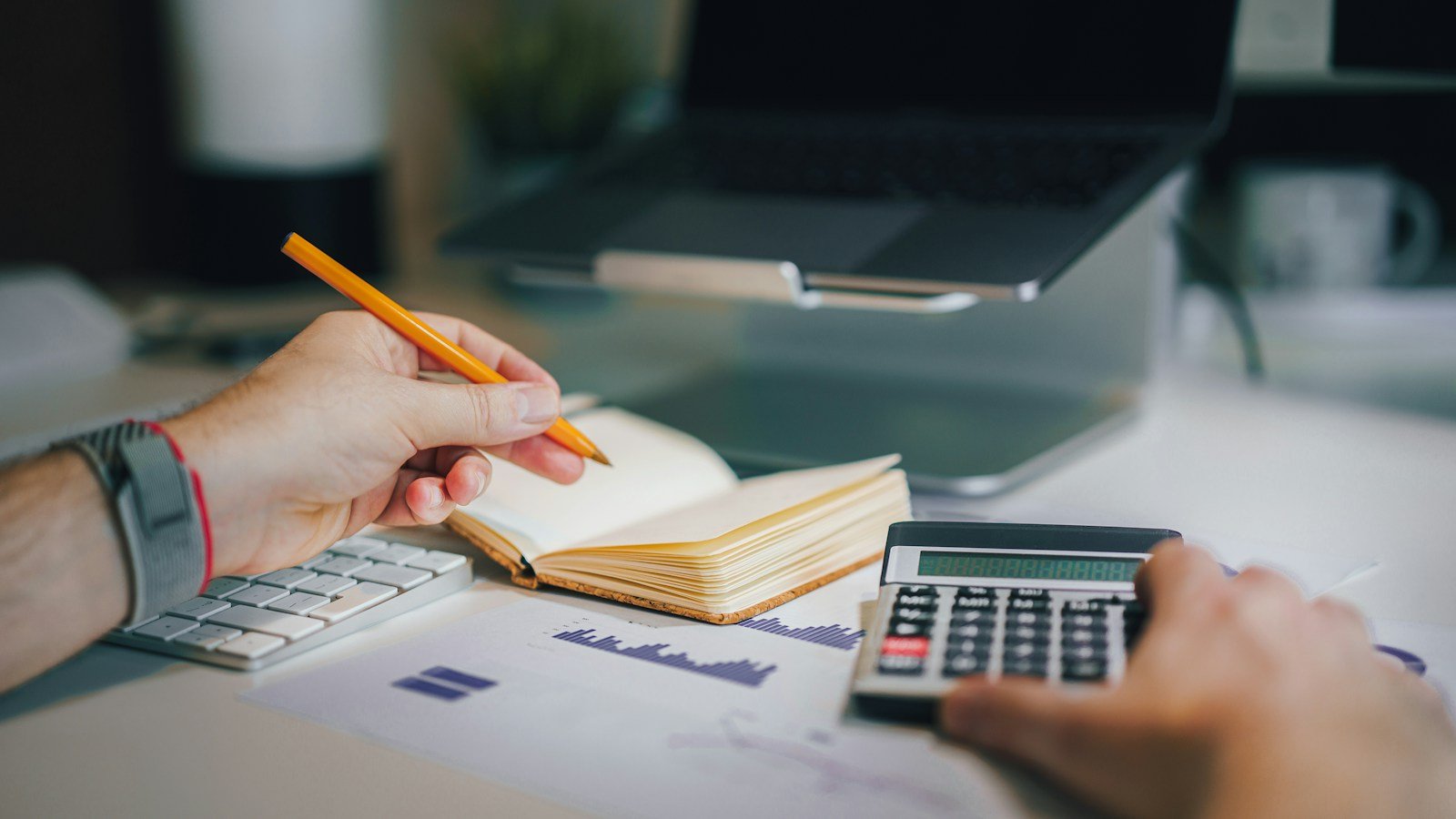 Person working at a desk with a calculator and notebook