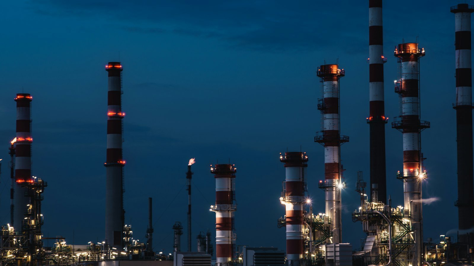 Oil refinery towers lit against a night sky
