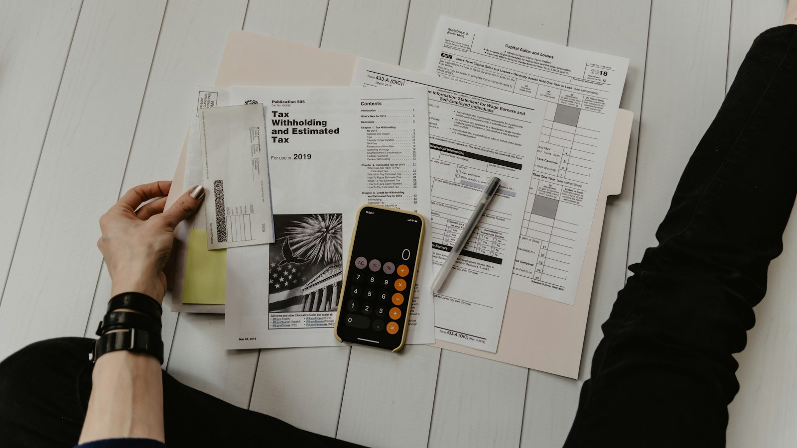 Person reviewing financial paperwork next to a pen and calculator