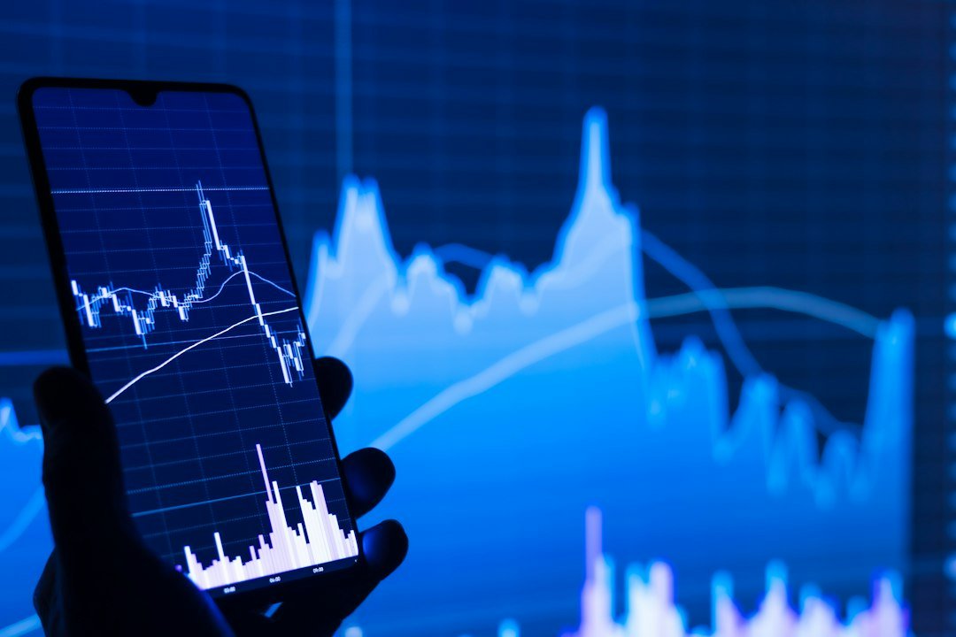 Person holding a phone in front of a stock chart